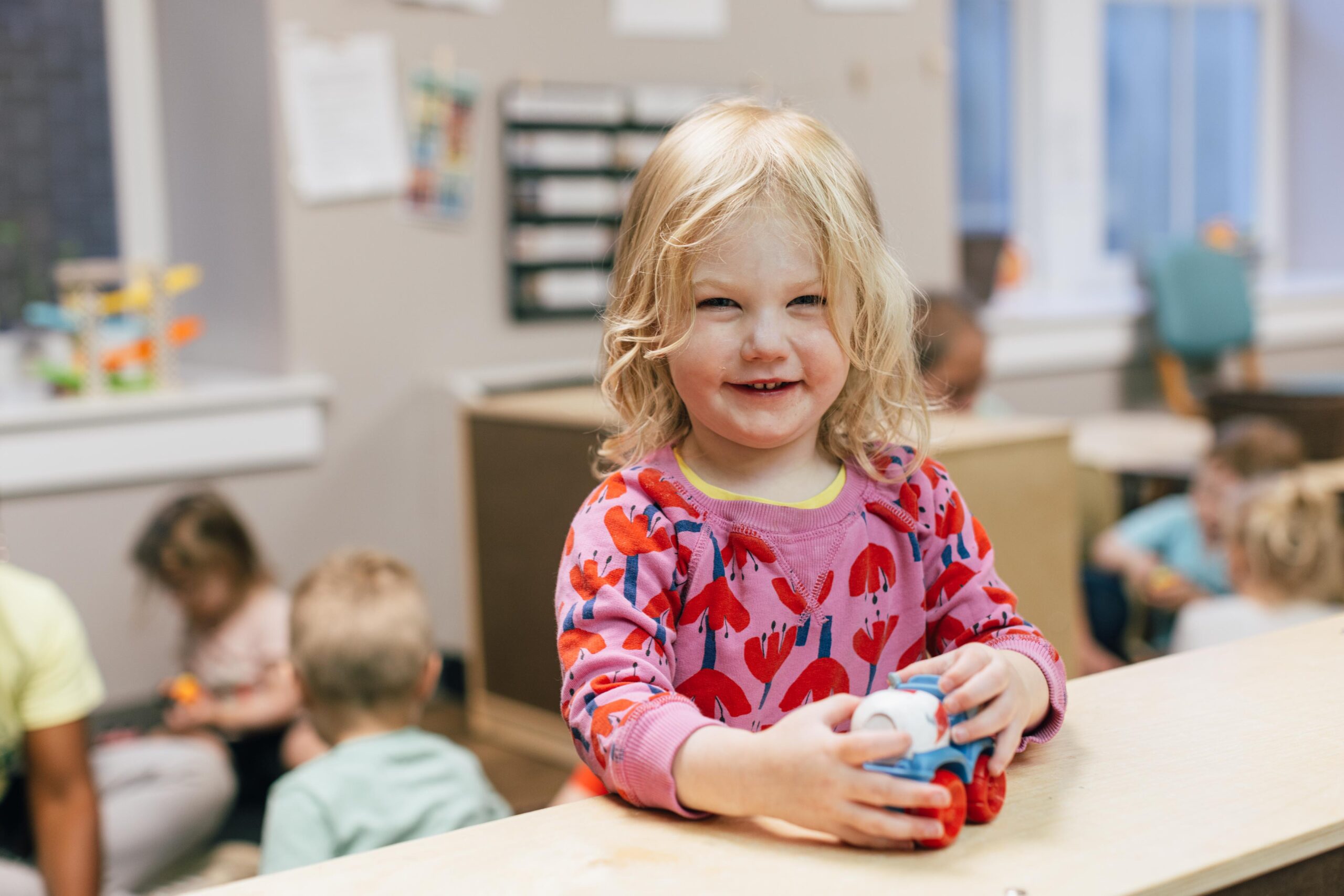 Toddler girl smiling and holding a toy