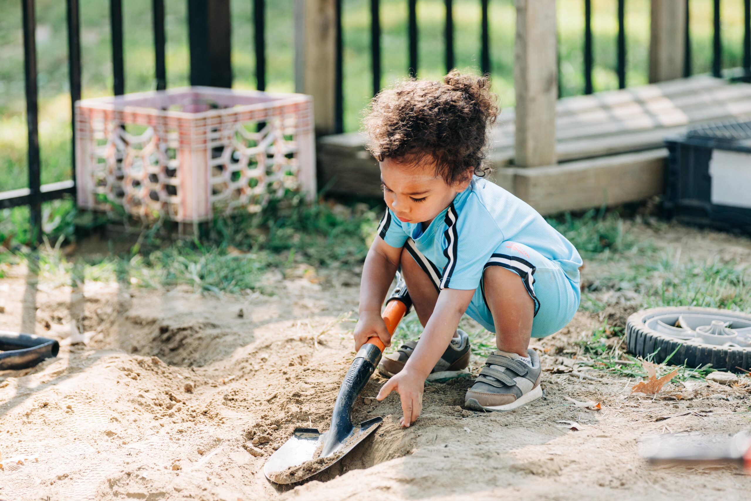 Young preschool boy digging in dirt on a playground