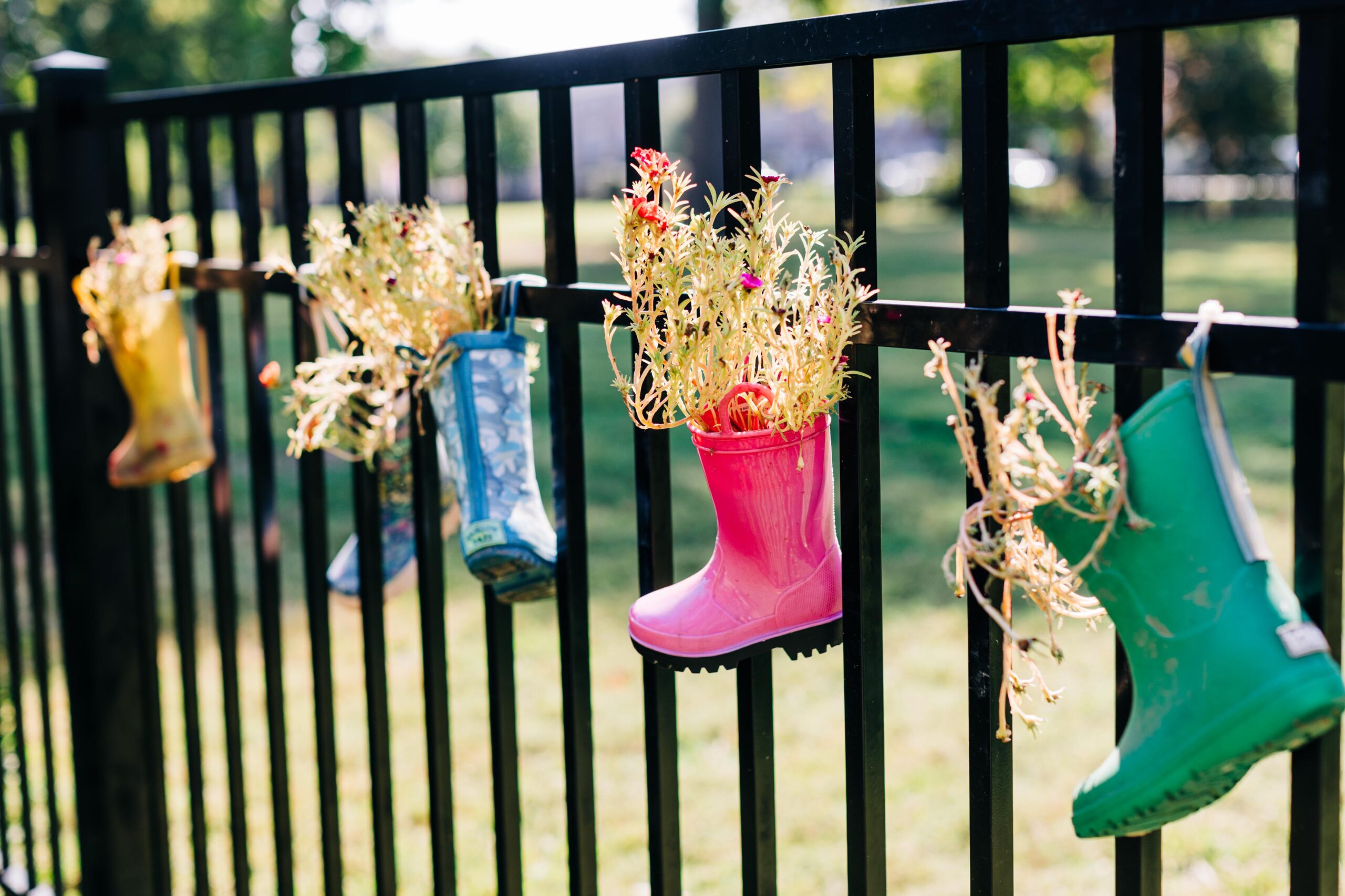 Natural playground with rain boots hanging on a fence with flowers in them