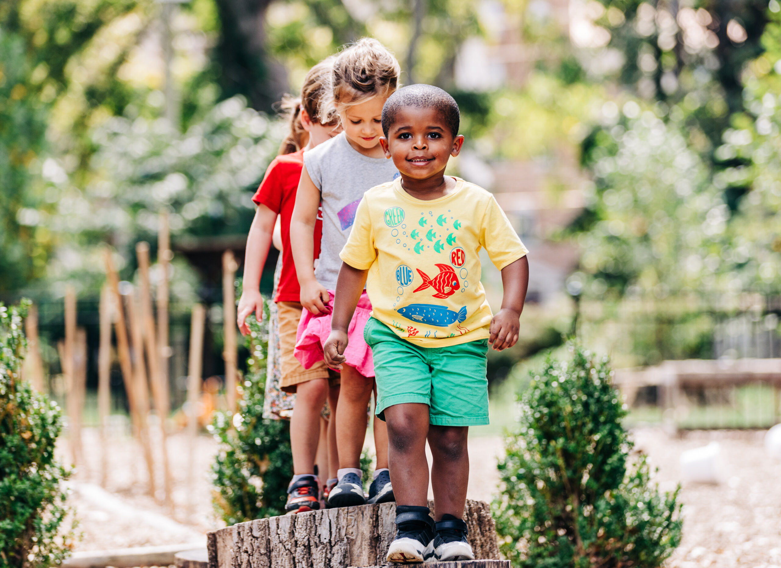 Young black boy playing on a stump on the playground