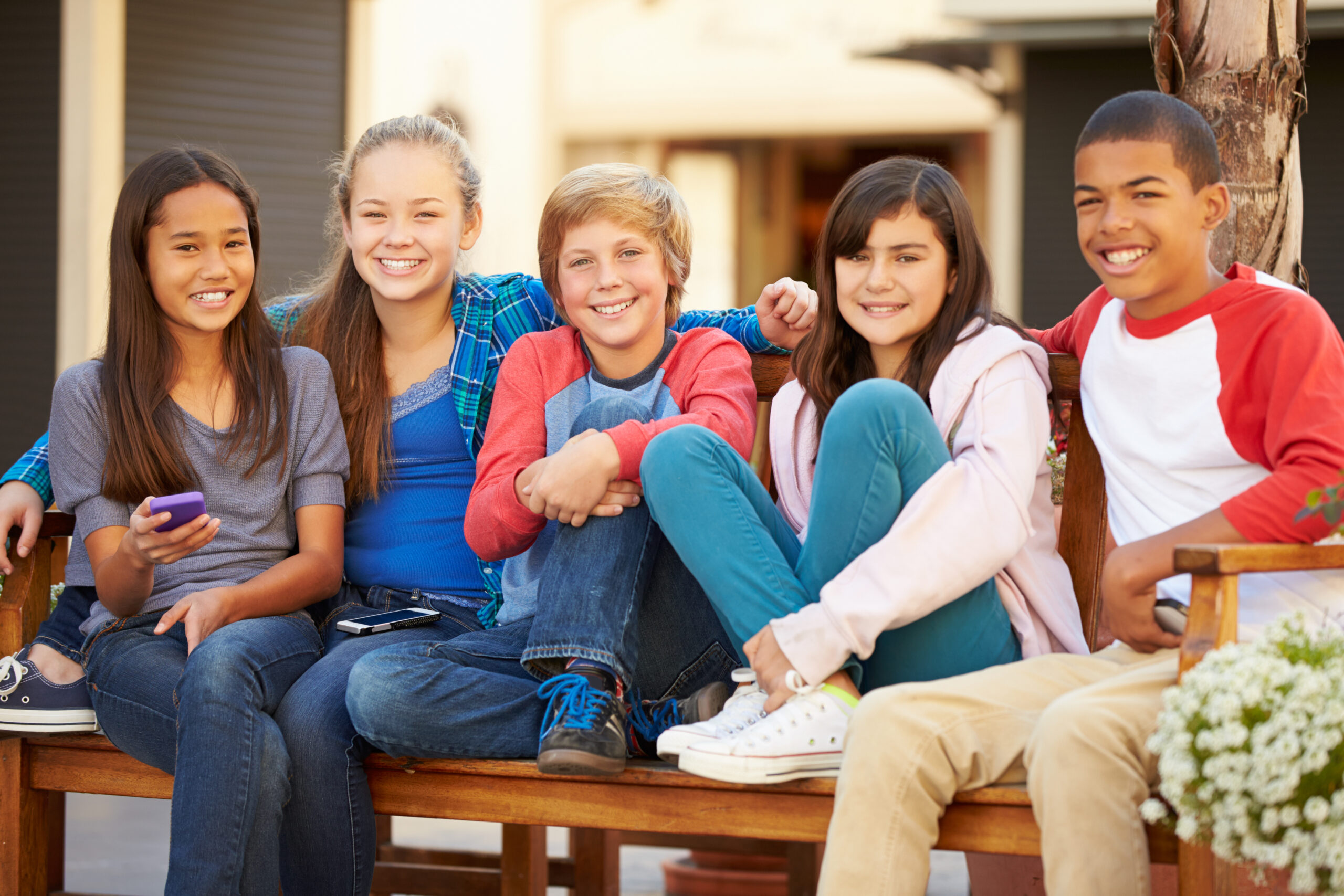 Group Of tween children Sitting On Bench In Mall